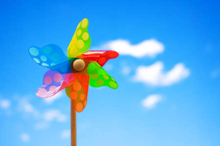 Pinwheel on blue sky with clouds. Colorful wheel kids toy.の写真素材