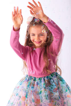 Girl in party dress playing with soap bubbles, christmas spirit.の写真素材