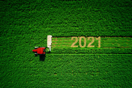 Tractor mowing green field, and happy new year 2021の写真素材