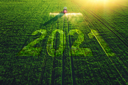 2021 Happy New Year concept and Aerial view of farming tractor plowing and spraying on field.の写真素材