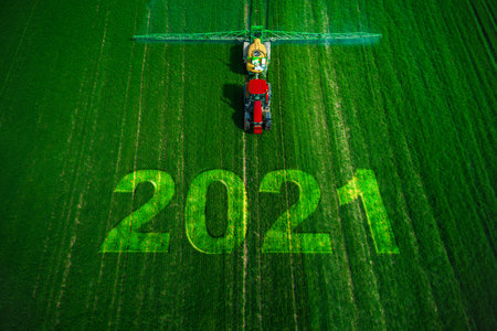2021 Happy New Year concept and Aerial view of farming tractor plowing and spraying on field.の写真素材