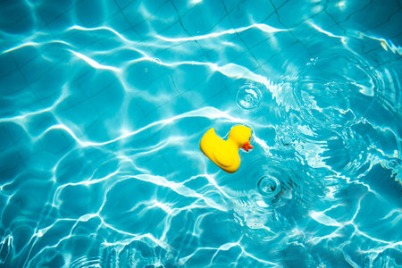 Yellow rubber duck toy on swimming pool and sun rays .の写真素材