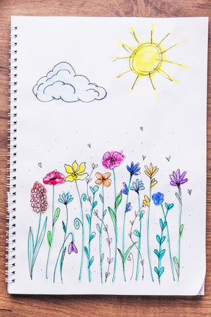Child drawing top view. Artwork workplace with creative accessories. Drawing sheet with artwork by daughter on tableの写真素材