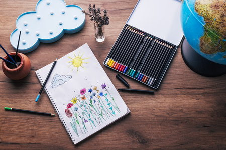 Child drawing top view. Artwork workplace with creative accessories. Drawing sheet with artwork by daughter on tableの写真素材
