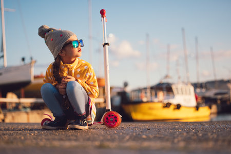 Little girl riding scooter outdoor near sea harbourの写真素材