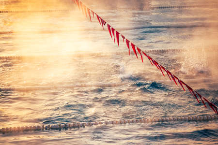 Corridor Lanes and flags in swimming pool with fog over the water. Sport Competition.の写真素材