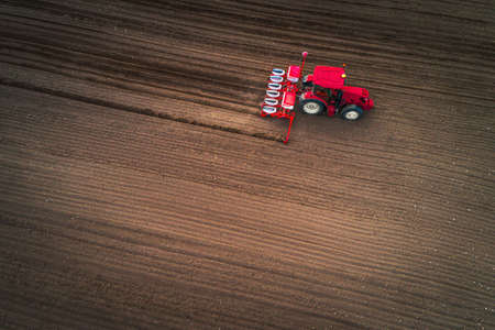 Farmer in tractor preparing farmland with seedbed for the next yearの写真素材
