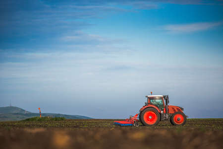 Farmer in tractor preparing land with seedbed cultivatorの写真素材