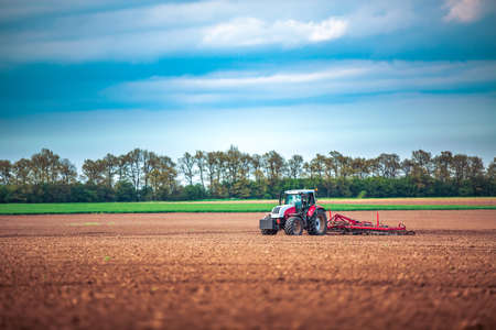 Farmer in tractor preparing land with seedbed cultivatorの写真素材