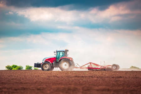 Farmer in tractor preparing land with seedbed cultivatorの写真素材