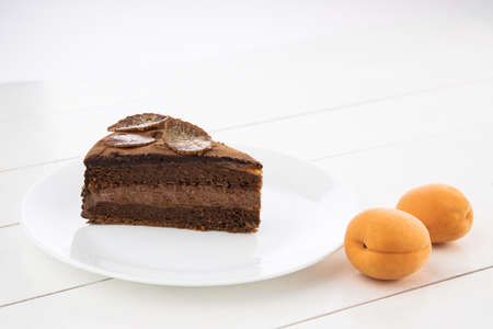 Piece of chocolate homemade cake with nuts and apricot jelly in a plateの写真素材