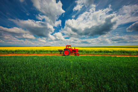 Tractor in the agricultural fields and dramatic cloudsの写真素材