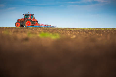Farmer in tractor preparing land with seedbed cultivatorの写真素材