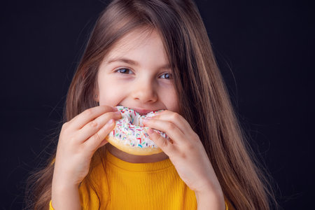 Sweet little girl eating white donutの写真素材