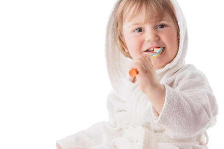 Little baby brushing his teeth under a white towelの写真素材