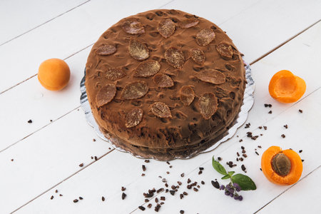 Chocolate homemade cake with nuts and apricot jelly on wooden backgroundの写真素材