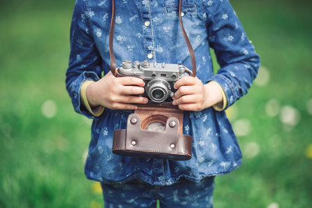 Little girl with old vintage camera making photos of surrounding nature in the parkの写真素材