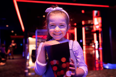 Little girl watching cartoon 3D movie in cinema and eating popcornの写真素材