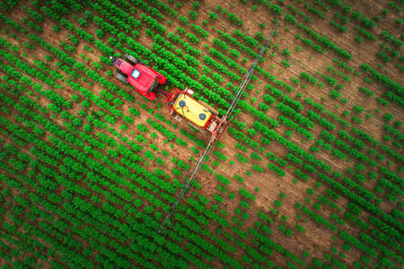 Farming tractor plowing and spraying on fieldの写真素材
