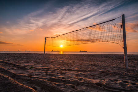 Volleyball net and sunrise on the beachの写真素材