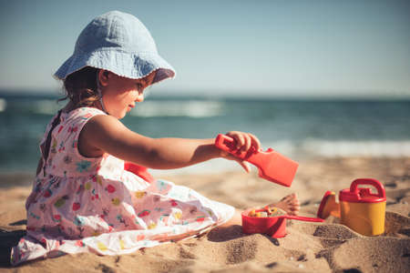 Little girl playing on the beach with toysの写真素材