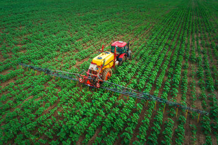 Farming tractor plowing and spraying on fieldの写真素材