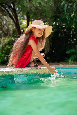 Portrait of young beautiful woman playing with water. Playful little girl in a park.の写真素材