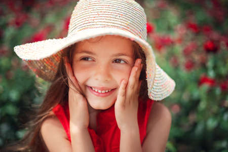 Beautiful little girl in roses garden in park. Charming woman smiling outdoor with flowers.の写真素材