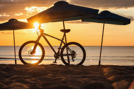 Silhouette of Beach Umbrellas with bike, sunrise shot.の写真素材