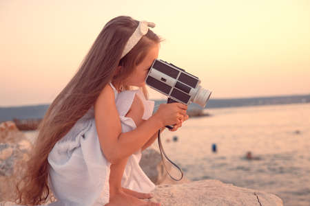 Happy Little Girl Enjoying Sea Sunset and Beach Using Retro Camera