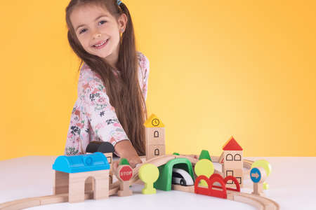 Cute kid, little girl playing with wooden toys train and railway roadの写真素材