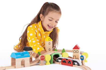Cute kid, little girl playing with wooden toys train and railway roadの写真素材