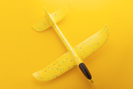 Yellow airplane toy isolated on yellow backgroundの写真素材
