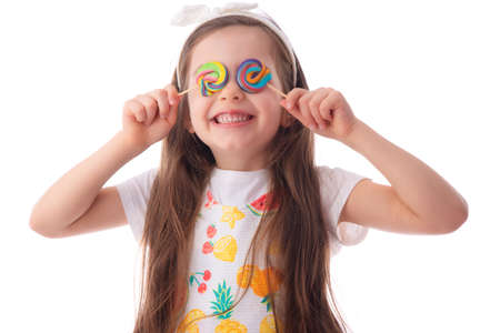 Little kid eating lollipop. Happy beautiful girl with candy isolated on white background.の写真素材