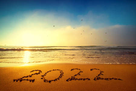 Happy New Year 2022 concept, lettering on the beach. Written text on the sea beach at sunrise.の写真素材