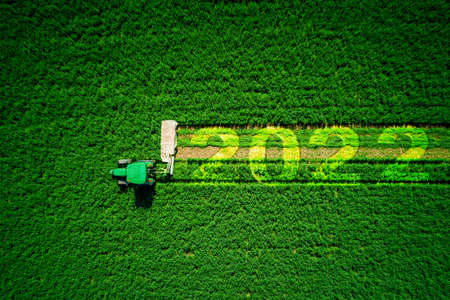 2022 Happy New Year concept and red tractor mowing green field.の写真素材