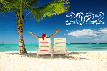 2022 new year concept with woman in santa's hat  relaxing on tropical beach.の写真素材