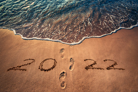 Happy New Year 2022 concept written on the sea beach at sunriseの写真素材