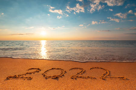 Happy New Year 2022 concept, lettering on the beach. Written text on the sea beach at sunrise.の写真素材