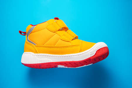 Yellow baby shoes. Kids sport sneakers isolated on blue backgroundの写真素材