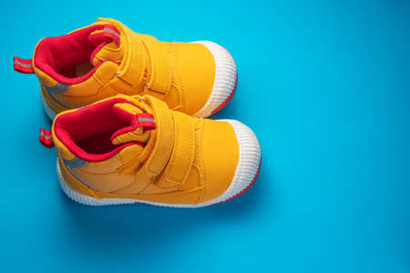 Yellow baby shoes. Kids sport sneakers isolated on blue backgroundの写真素材