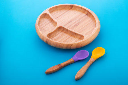 Wooden bowl. Bamboo plate with spoon isolated on blue backgroundの写真素材