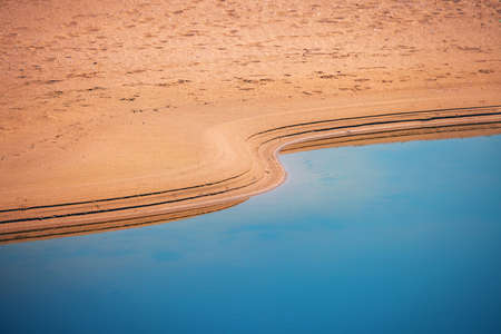 Oasis in a desert. Sand and water, prints of waves.の写真素材