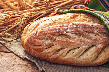 Fresh oven baked homemade sourdough bread in folklore bag. Bulgarian traditions and symbol of farmland field and farmer.の写真素材