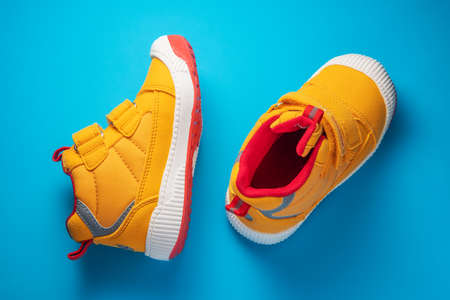 Yellow baby shoes. Kids sport sneakers isolated on blue backgroundの写真素材