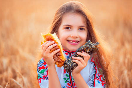 Bulgarian girl, beautiful woman, eating freshly baked banitsa, cheese pie during harvest In golden wheat fieldの写真素材