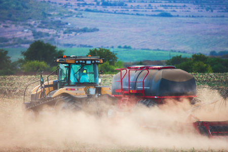 Farmer in tractor preparing land with seedbed cultivatorの写真素材