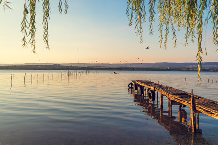 Sunset over the sea lake and old wooden pier, romantic travel destination, nature landscapeの写真素材