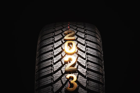 Happy new year 2023 and winter Car tire for snow isolated on black background. New automobile tyre...