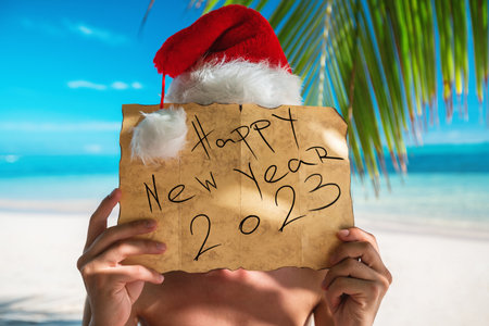 Happy new year 2023 Tourist man with Santa Claus hat relaxing on tropical island beach. Punta Cana, Dominican Republic.の写真素材